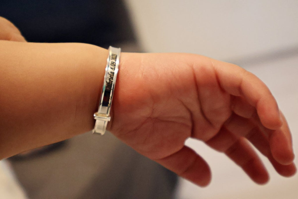 Sterling silver baby bangle with enamel daisy, heart, or crown. Expandable, engravable, perfect keepsake.