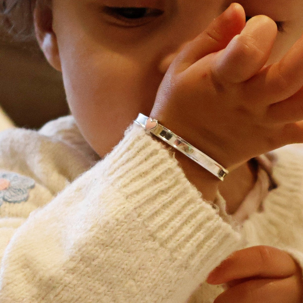 Sterling silver baby bangle with enamel daisy, heart, or crown. Expandable, engravable, perfect keepsake.