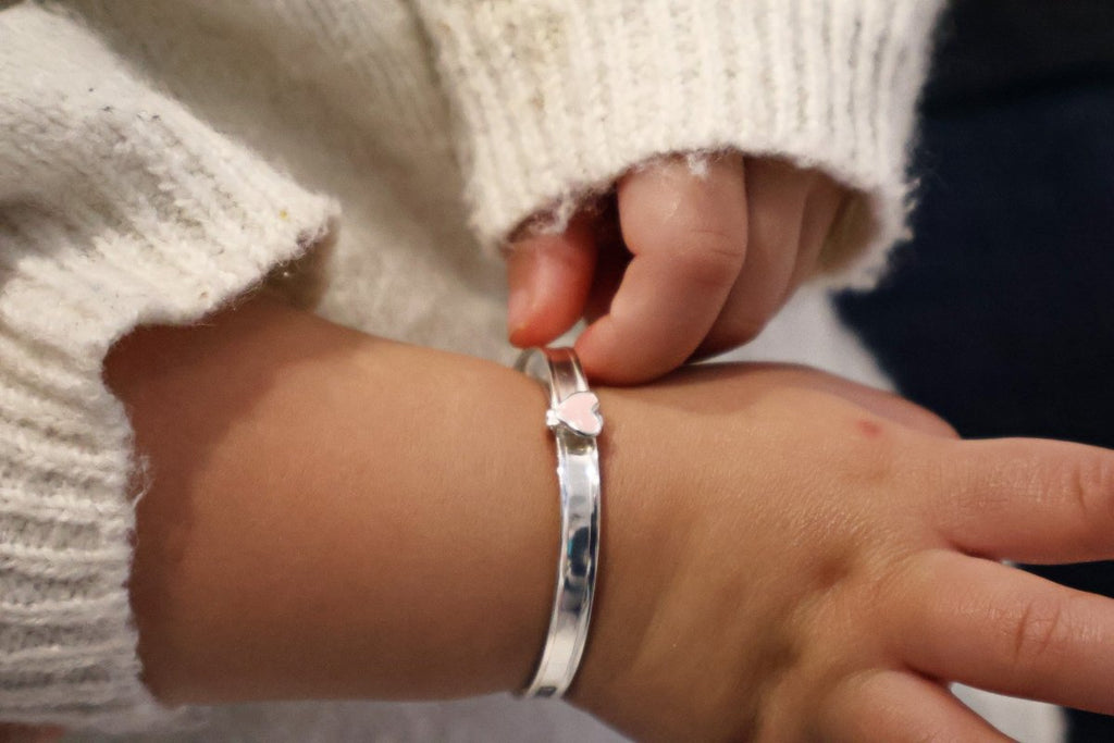 Sterling silver baby bangle with enamel daisy, heart, or crown. Expandable, engravable, perfect keepsake.